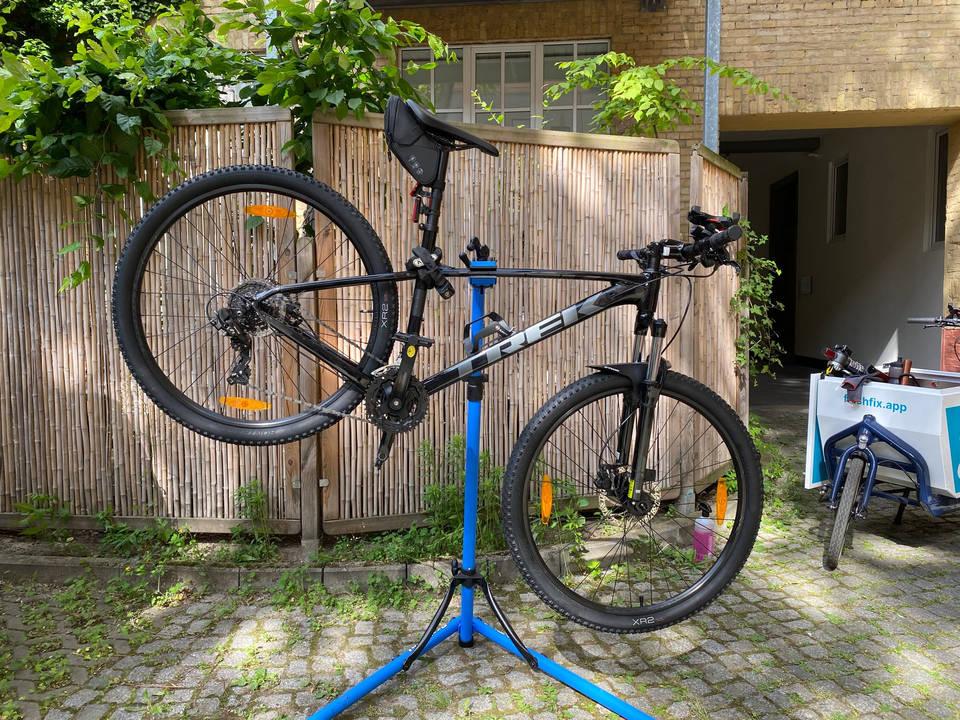 A large black MTB hanging on a bike stand.